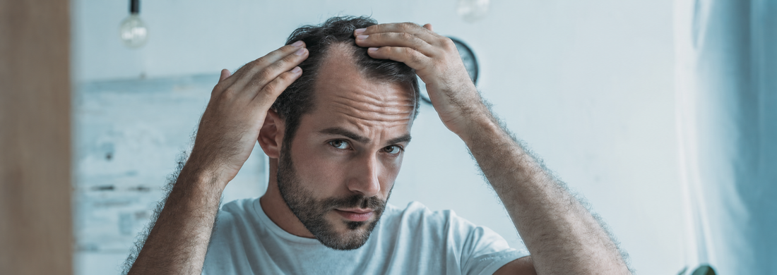 Man checking a thinning hairline while learning about hair-loss myths and causes